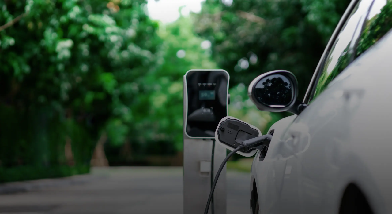Véhicule électrique blanc branché sur une borne de recharge.